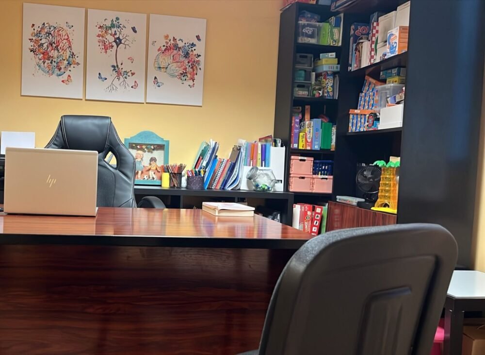 Mesa del despacho de Beatriz, con láminas de cerebros en flor y una estantería llena de juegos